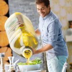 Guy pouring olive oil on the salad